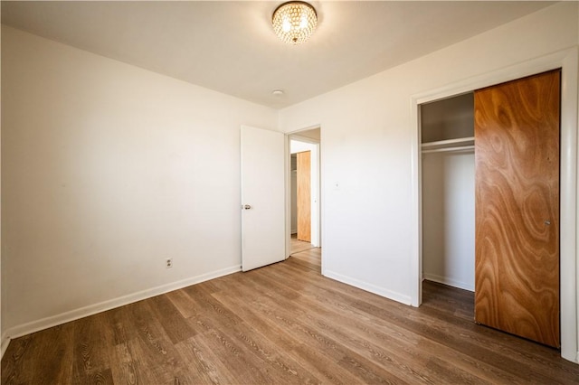 unfurnished bedroom featuring a closet, wood finished floors, and baseboards