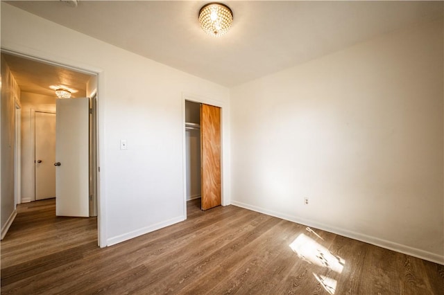 unfurnished bedroom with a closet, baseboards, and wood finished floors