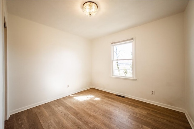 spare room featuring visible vents, baseboards, and wood finished floors