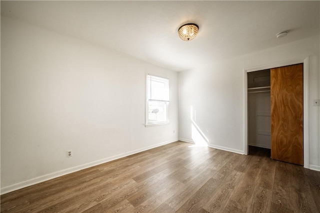 unfurnished bedroom featuring a closet, baseboards, and wood finished floors