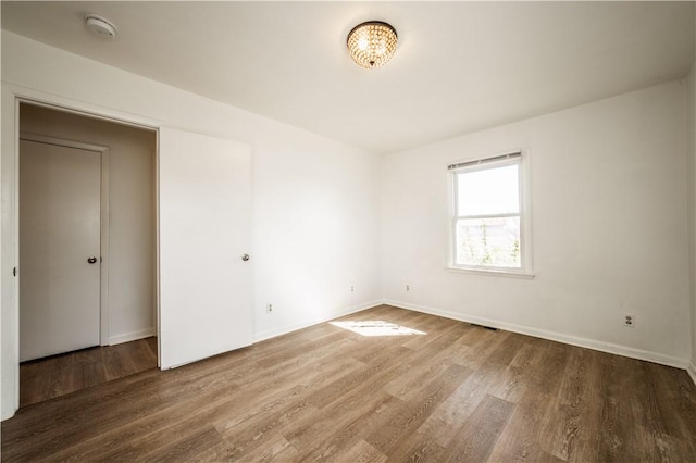 unfurnished bedroom featuring visible vents, baseboards, and wood finished floors