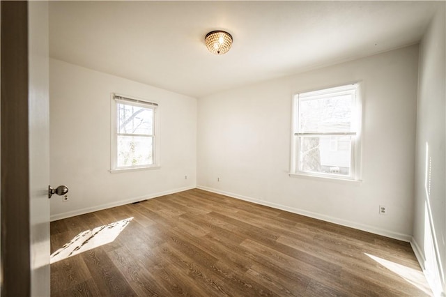 spare room featuring baseboards and dark wood-style flooring