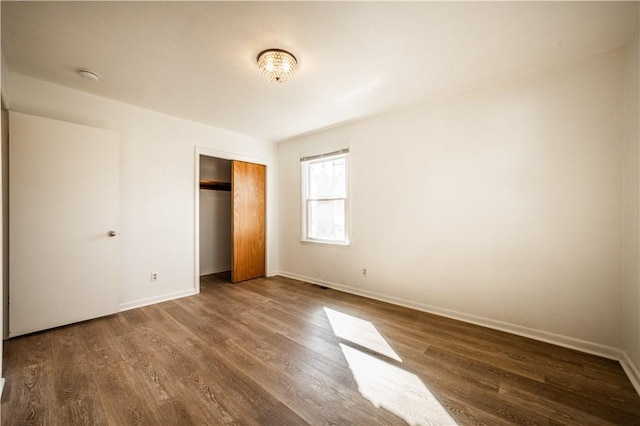 unfurnished bedroom with a closet, baseboards, and wood finished floors