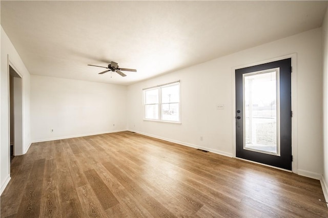 spare room featuring ceiling fan, wood finished floors, visible vents, and baseboards