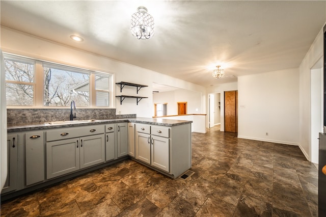 kitchen with a peninsula, visible vents, a sink, and gray cabinetry