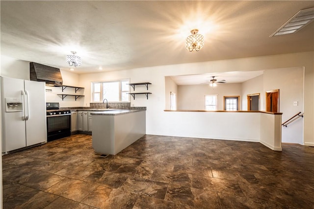 kitchen with open shelves, visible vents, wall chimney range hood, white fridge with ice dispenser, and gas range