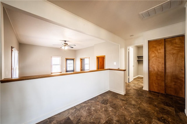 unfurnished room featuring a ceiling fan, visible vents, and baseboards