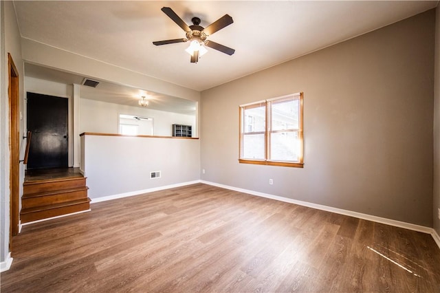 spare room featuring visible vents, ceiling fan, baseboards, and wood finished floors