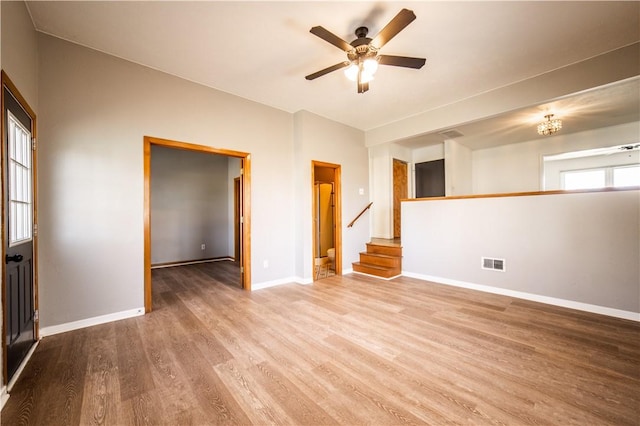 empty room featuring stairs, visible vents, baseboards, and wood finished floors