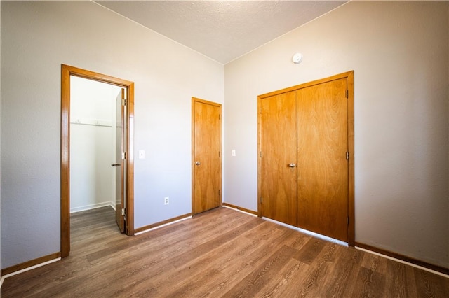 unfurnished bedroom featuring a closet, wood finished floors, and baseboards