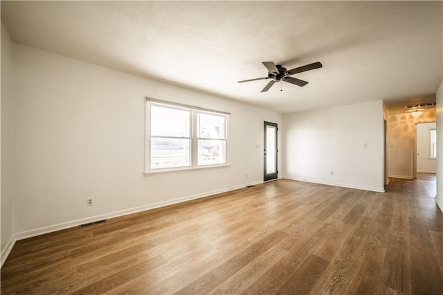 unfurnished room featuring ceiling fan, wood finished floors, visible vents, and baseboards