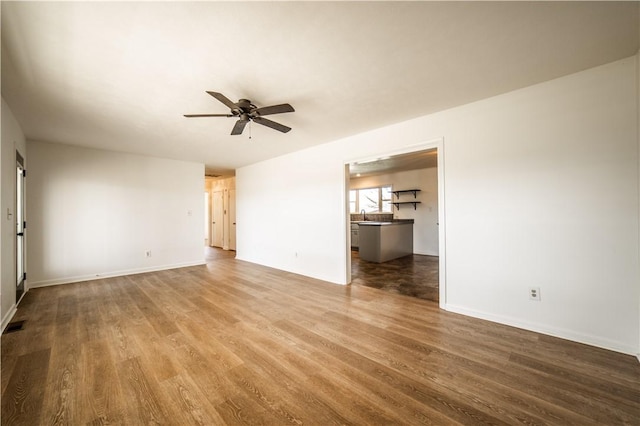 unfurnished living room featuring ceiling fan, baseboards, and wood finished floors