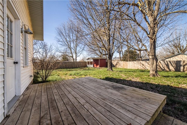 wooden terrace with a shed, a lawn, an outdoor structure, and a fenced backyard