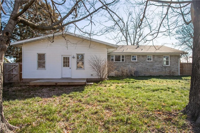 back of house with a deck, a yard, brick siding, and fence