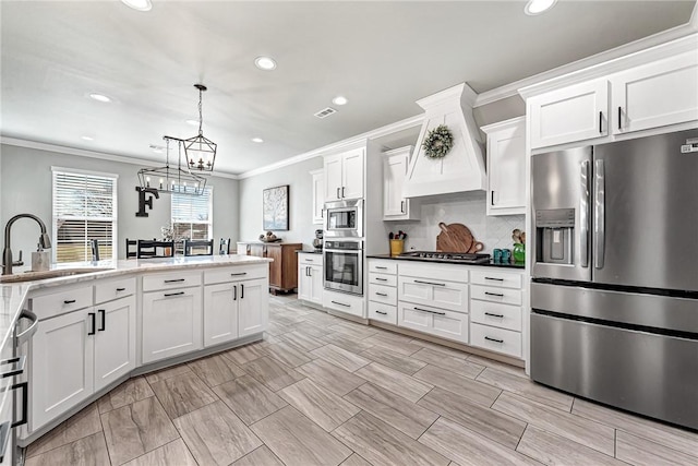 kitchen with decorative light fixtures, stainless steel appliances, backsplash, white cabinetry, and a sink