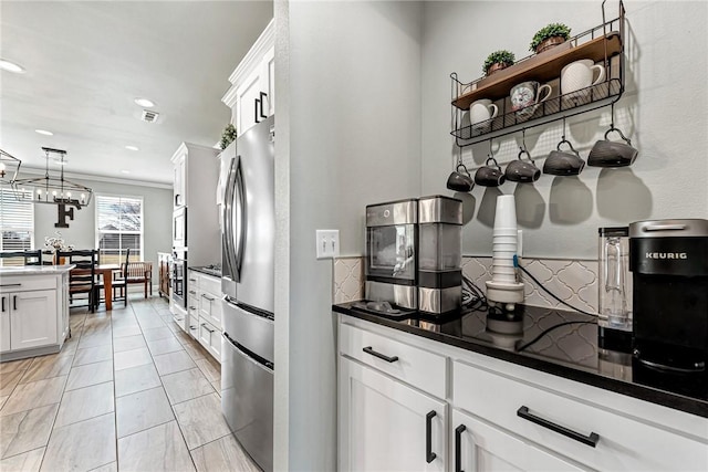 kitchen with stainless steel appliances, dark countertops, white cabinets, and hanging light fixtures