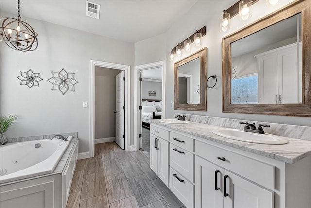 ensuite bathroom featuring double vanity, a jetted tub, a sink, and visible vents