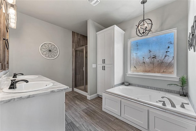 bathroom with a tub with jets, a stall shower, a sink, and baseboards