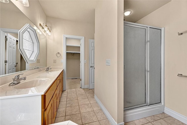 full bath with double vanity, a stall shower, baseboards, and a sink