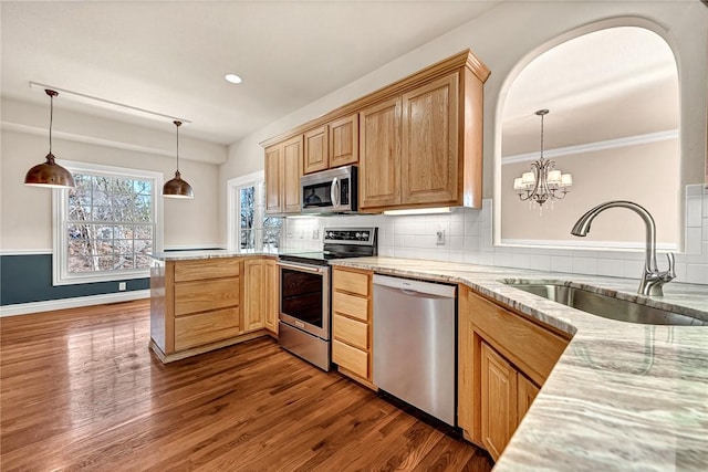 kitchen with stainless steel appliances, tasteful backsplash, dark wood-type flooring, a sink, and a peninsula