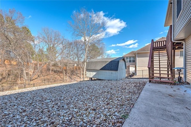 exterior space featuring a storage unit, stairway, an outdoor structure, and fence