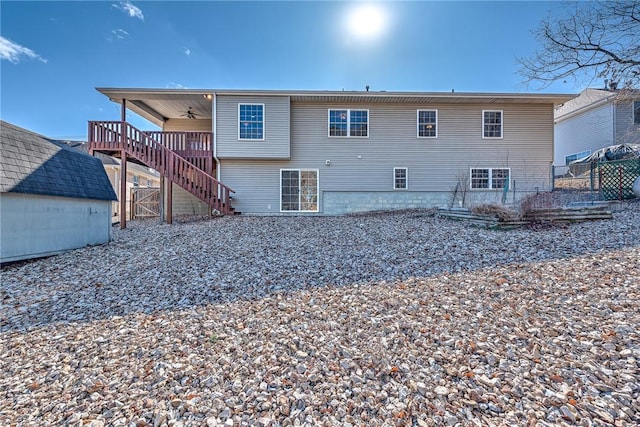 rear view of property featuring ceiling fan, fence, stairway, and an outbuilding