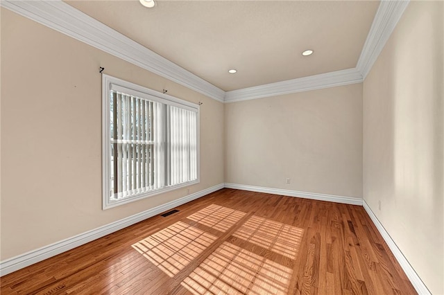 unfurnished room with visible vents, crown molding, baseboards, and wood finished floors