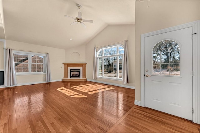 entryway with a fireplace with raised hearth, hardwood / wood-style flooring, and a ceiling fan