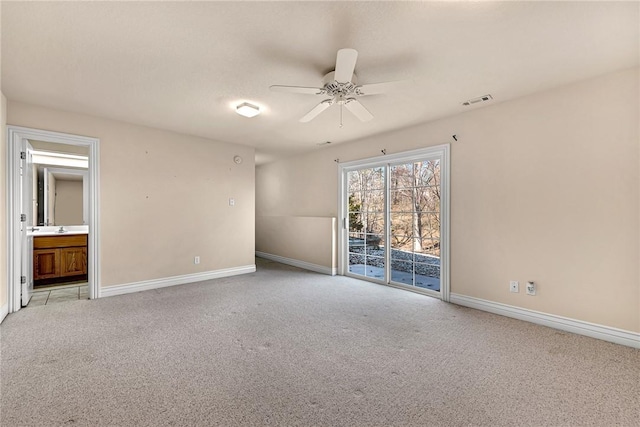 empty room with ceiling fan, a sink, visible vents, baseboards, and carpet