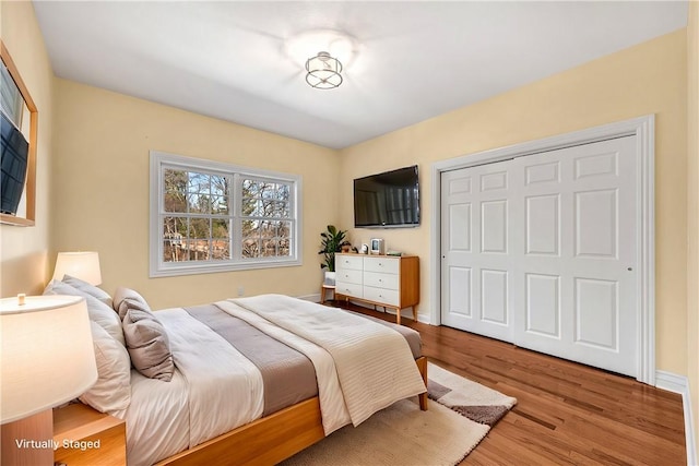 bedroom with a closet, wood finished floors, and baseboards