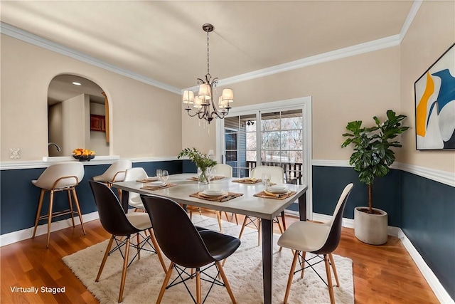 dining area featuring a notable chandelier, crown molding, baseboards, and wood finished floors