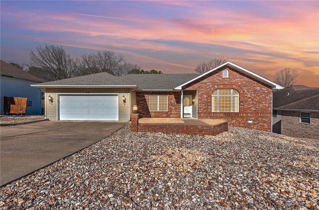 ranch-style home featuring a garage, brick siding, driveway, and a shingled roof