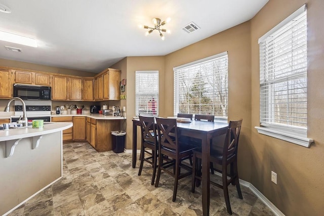 kitchen featuring visible vents, black microwave, light countertops, and electric range