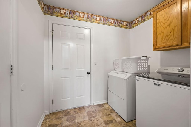 laundry area featuring separate washer and dryer, cabinet space, and baseboards