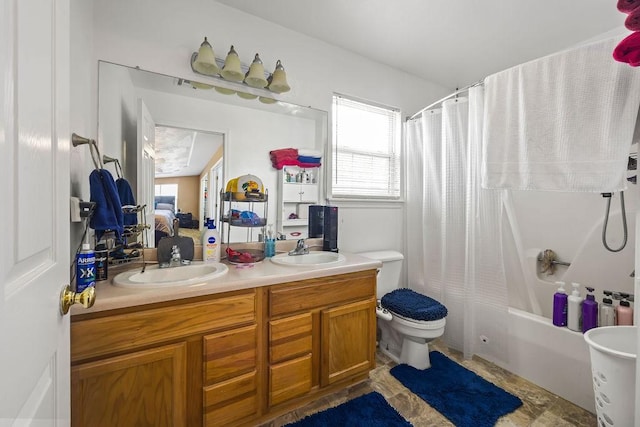 bathroom with toilet, double vanity, a sink, and a wealth of natural light