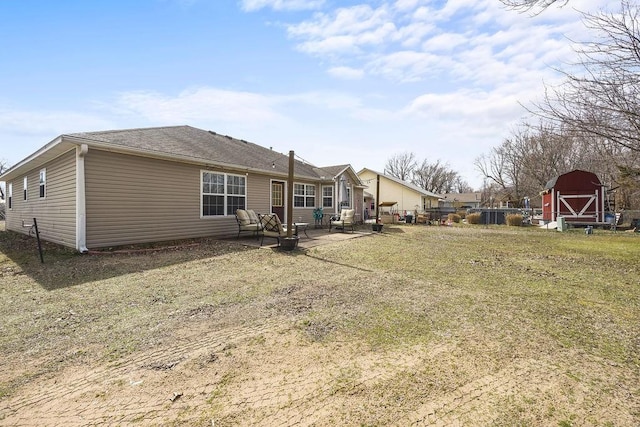 back of house featuring a shed, an outbuilding, a lawn, and a patio