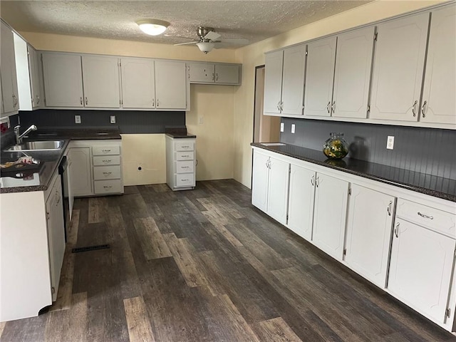 kitchen with dark countertops, ceiling fan, dark wood-style flooring, a textured ceiling, and a sink