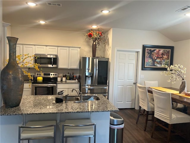 kitchen with appliances with stainless steel finishes, a breakfast bar area, visible vents, and white cabinetry