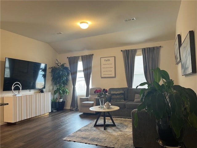 living area with lofted ceiling, visible vents, and dark wood finished floors