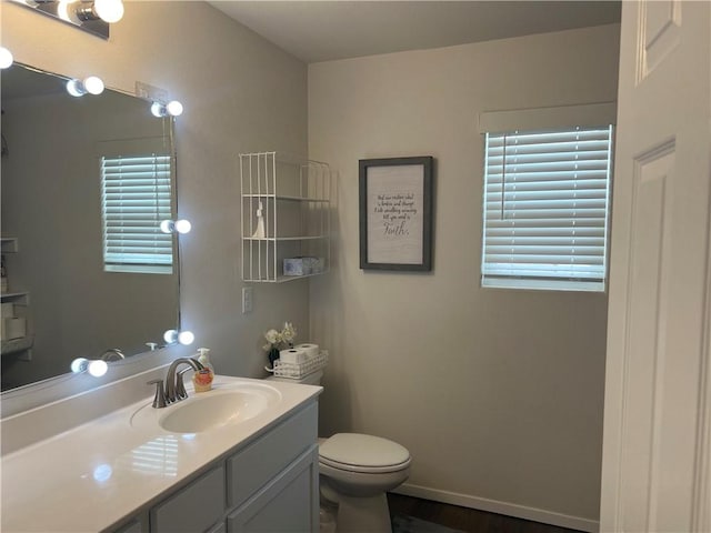 bathroom featuring toilet, baseboards, and vanity