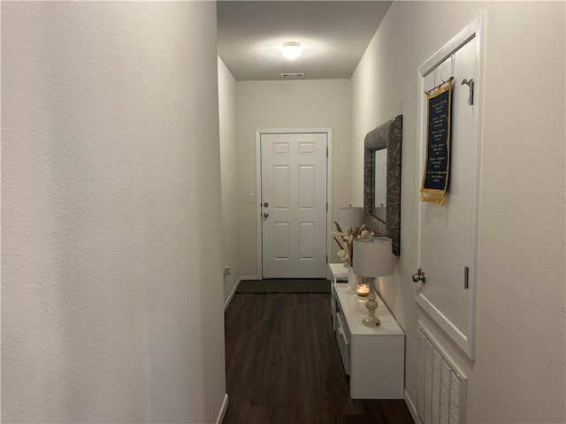 hallway featuring dark wood-type flooring, visible vents, and baseboards