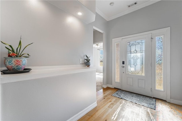 entrance foyer with crown molding, plenty of natural light, light wood-style floors, and visible vents