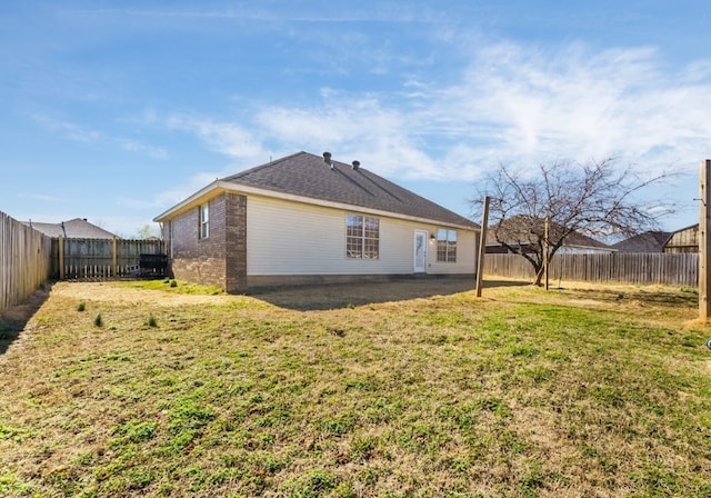 rear view of property featuring a yard, brick siding, and a fenced backyard