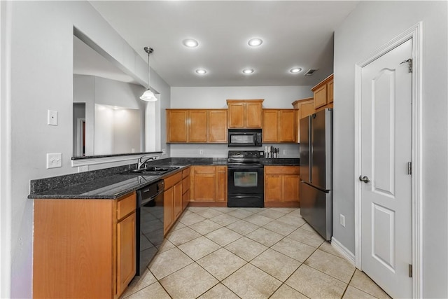 kitchen featuring pendant lighting, dark stone countertops, brown cabinetry, black appliances, and a sink