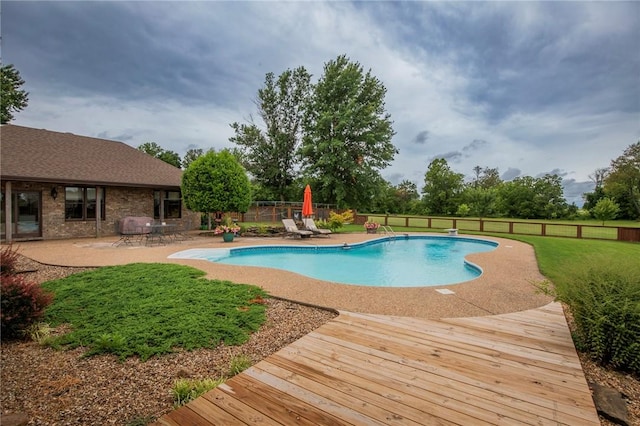 outdoor pool with a yard, a fenced backyard, and a patio