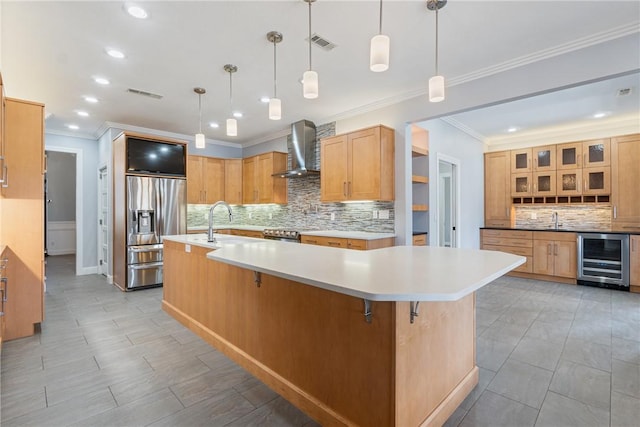 kitchen with wine cooler, visible vents, wall chimney range hood, appliances with stainless steel finishes, and a large island with sink