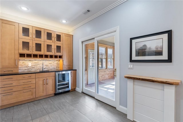 bar featuring indoor wet bar, decorative backsplash, ornamental molding, a sink, and beverage cooler