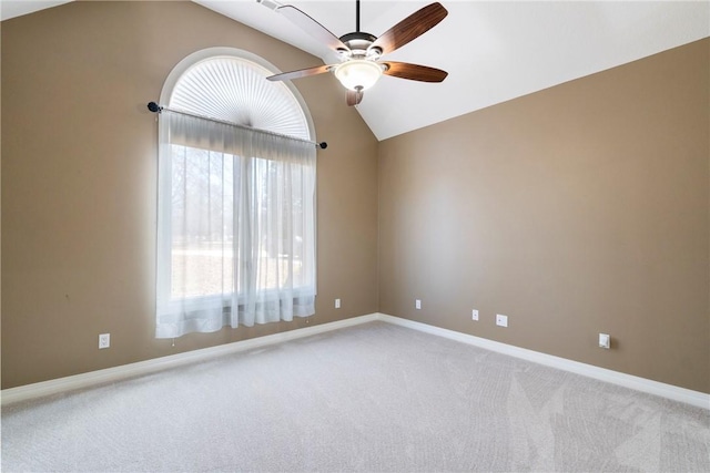 carpeted empty room featuring lofted ceiling, ceiling fan, and baseboards