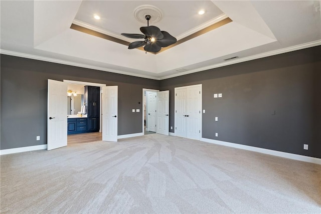 unfurnished bedroom featuring ornamental molding, a tray ceiling, and baseboards