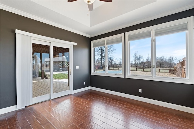 empty room with a ceiling fan, baseboards, a raised ceiling, and dark wood-type flooring